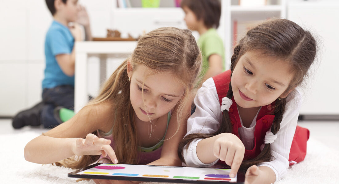 Two young girls learning on a tablet